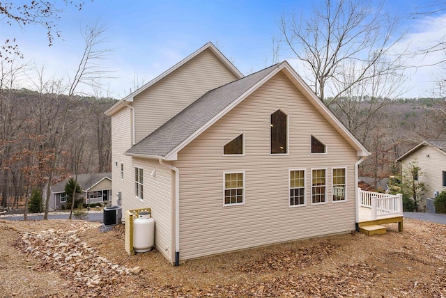 back of house with roof with shingles and central AC unit