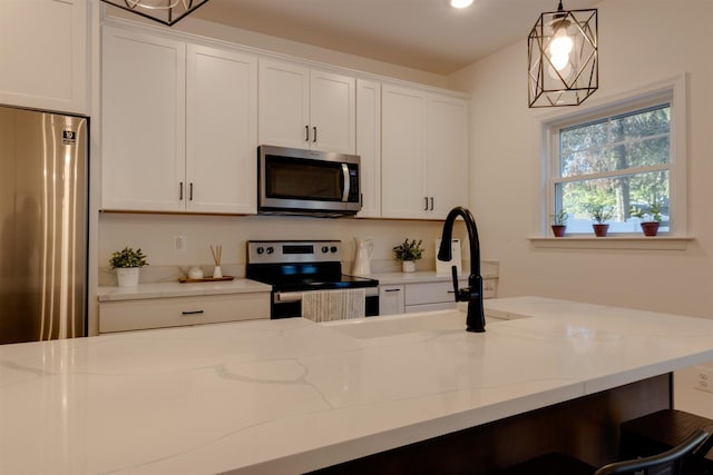 kitchen with light stone countertops, decorative light fixtures, stainless steel appliances, and white cabinets