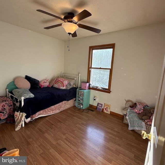 bedroom featuring wood finished floors, a ceiling fan, and baseboards