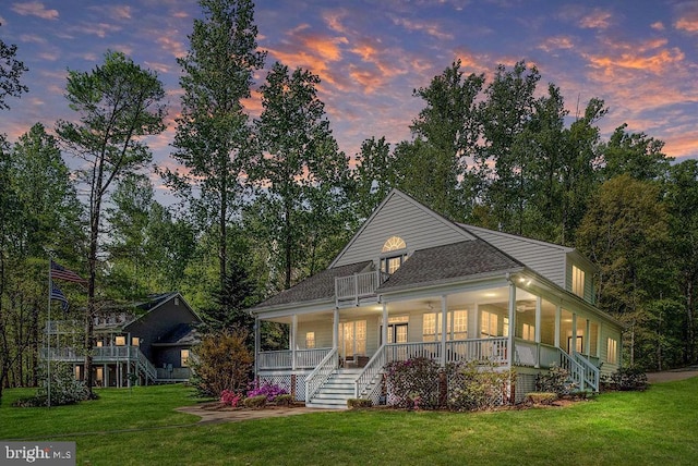 view of front of house with covered porch, stairway, and a yard