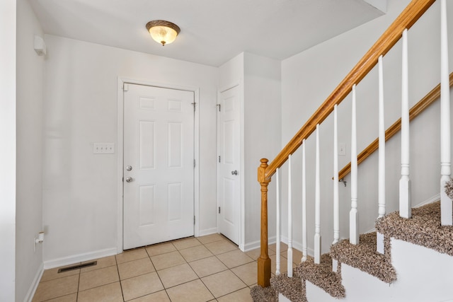 entryway featuring stairs, visible vents, baseboards, and light tile patterned floors