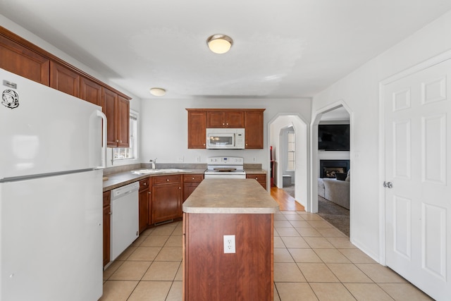 kitchen with white appliances, light tile patterned floors, a kitchen island, light countertops, and a sink