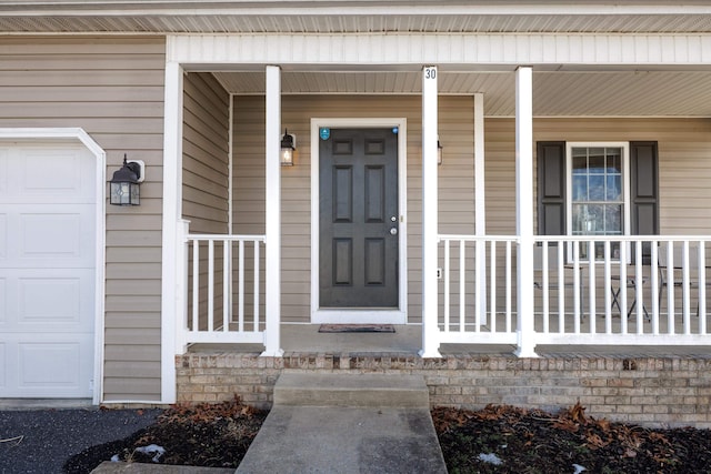 view of exterior entry featuring a garage and a porch