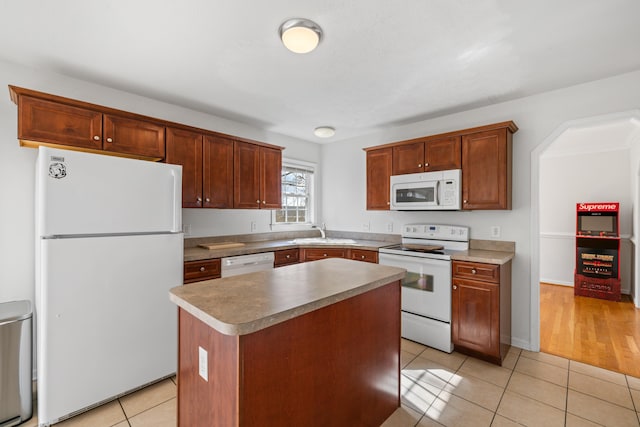 kitchen with a center island, light tile patterned floors, light countertops, a sink, and white appliances