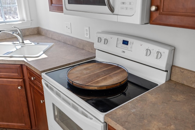 kitchen with light countertops, white appliances, a sink, and brown cabinets