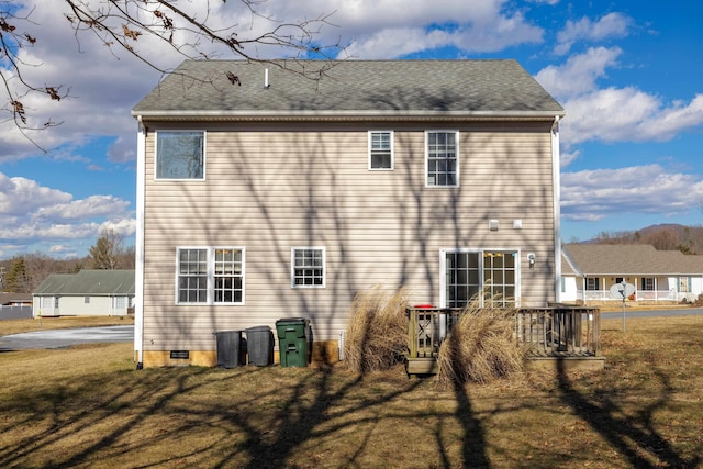 rear view of house featuring roof with shingles and a lawn