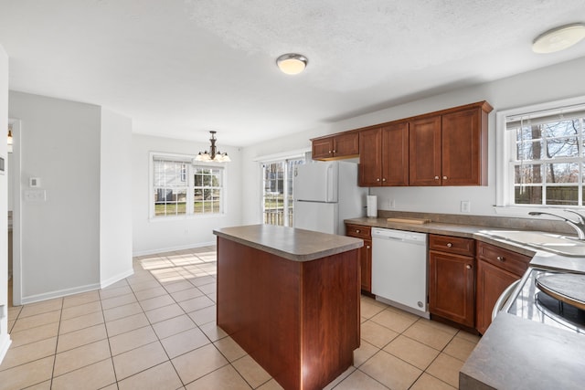 kitchen featuring decorative light fixtures, light tile patterned floors, a kitchen island, a sink, and white appliances