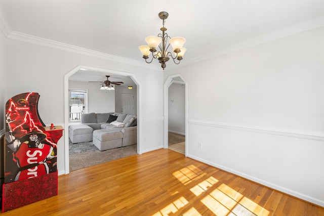 interior space with arched walkways, ornamental molding, wood finished floors, baseboards, and ceiling fan with notable chandelier