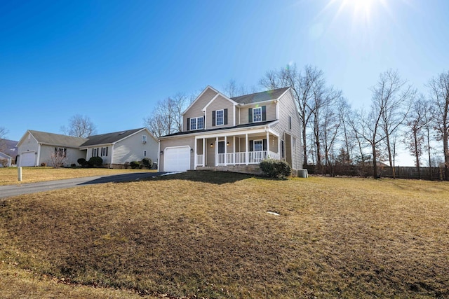 traditional home with aphalt driveway, covered porch, a front lawn, and an attached garage