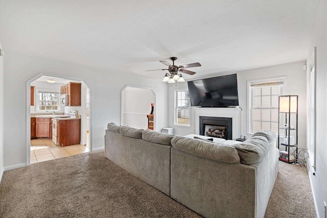 living area with light carpet, a fireplace, arched walkways, and a wealth of natural light