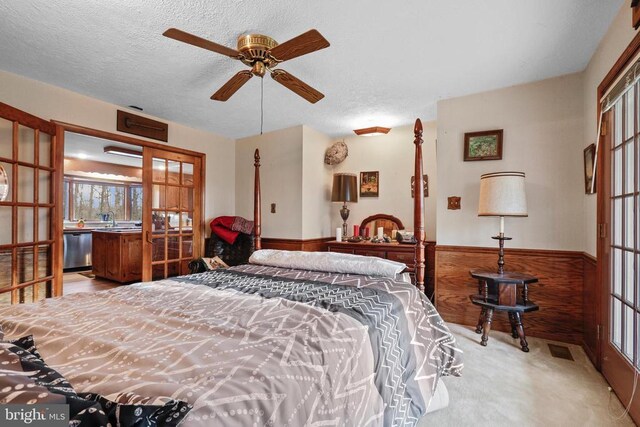 carpeted bedroom with sink, a textured ceiling, and wood walls