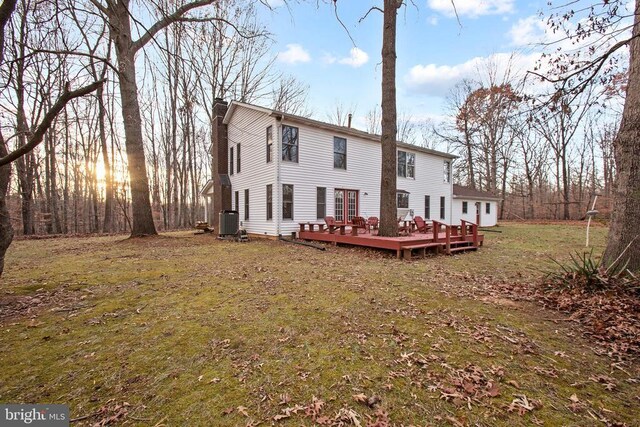 back house at dusk with a wooden deck, a yard, and central AC