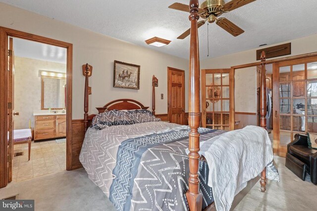 carpeted bedroom featuring stainless steel fridge, a textured ceiling, and ensuite bath