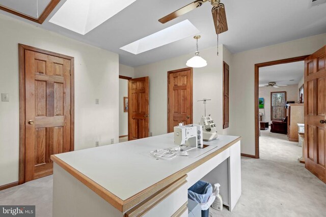 kitchen with hanging light fixtures, a center island, light carpet, and a skylight