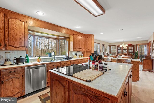 kitchen featuring stainless steel dishwasher, a center island, sink, and a wealth of natural light