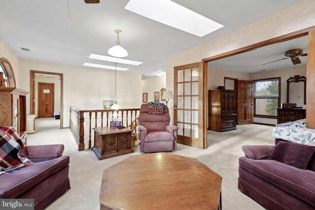 carpeted living room with a baseboard heating unit, a skylight, and ceiling fan