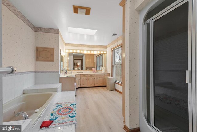 bathroom featuring vanity, hardwood / wood-style flooring, a skylight, and separate shower and tub