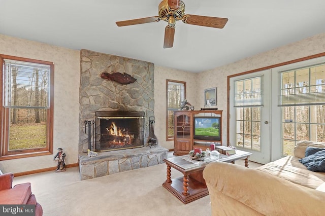 living room with a stone fireplace, carpet floors, and ceiling fan