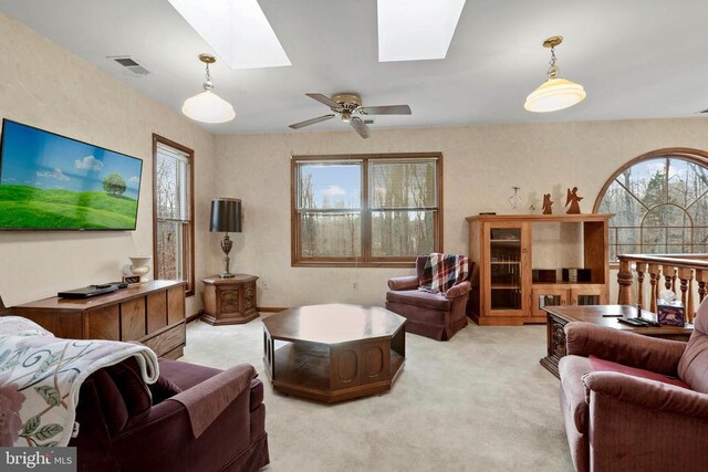 carpeted living room with ceiling fan and a skylight