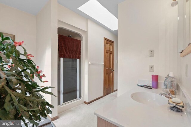 bathroom with an enclosed shower, vanity, and a skylight