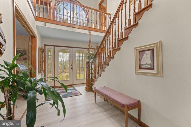 foyer entrance featuring a high ceiling, light hardwood / wood-style floors, and french doors