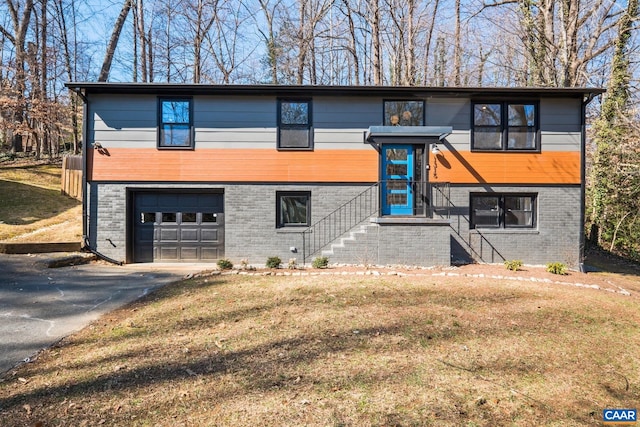 view of front of home featuring a front lawn, brick siding, driveway, and an attached garage