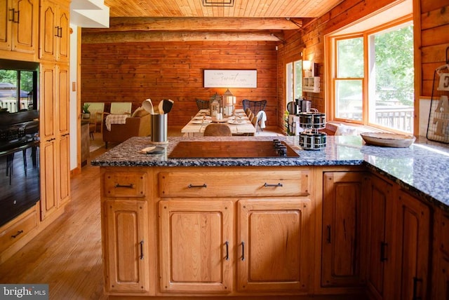 kitchen featuring light wood finished floors, wooden walls, wood ceiling, dark stone countertops, and black appliances