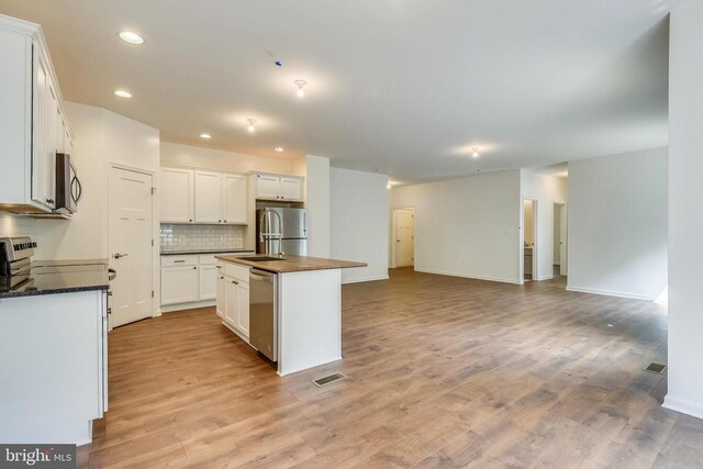 kitchen with tasteful backsplash, light hardwood / wood-style flooring, a center island with sink, stainless steel appliances, and white cabinets