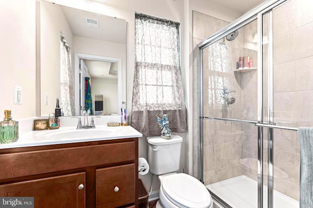 bathroom with visible vents, a shower stall, toilet, and vanity