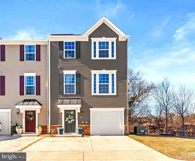 townhome / multi-family property featuring a garage, concrete driveway, and central air condition unit