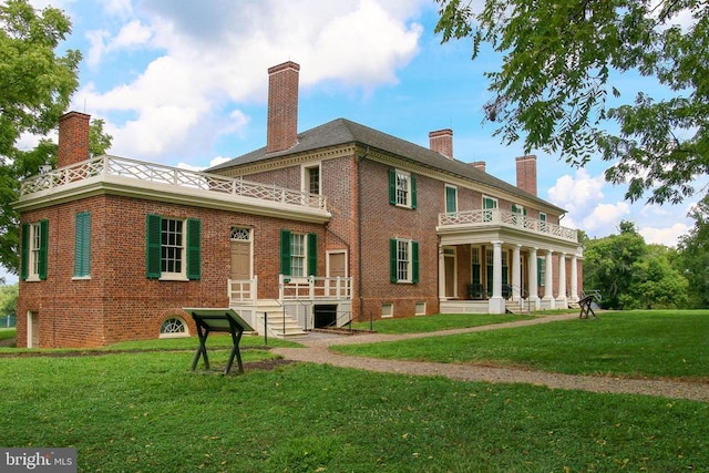 rear view of house with a chimney, a yard, and brick siding
