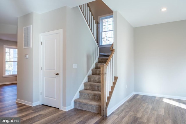 staircase with baseboards, visible vents, a healthy amount of sunlight, and wood finished floors