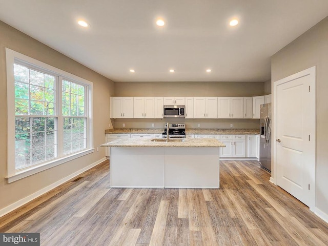 kitchen featuring a sink, baseboards, stainless steel appliances, and light wood finished floors