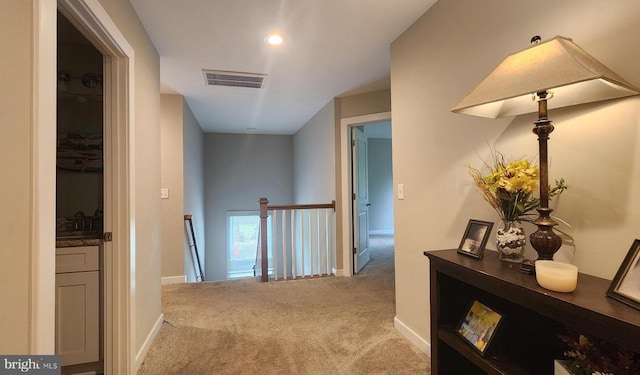 hallway featuring baseboards, carpet flooring, and visible vents