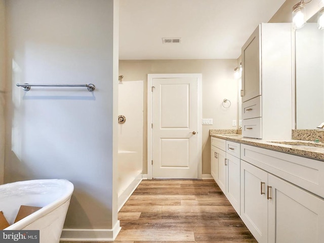 full bath with a sink, double vanity, wood finished floors, a shower, and visible vents