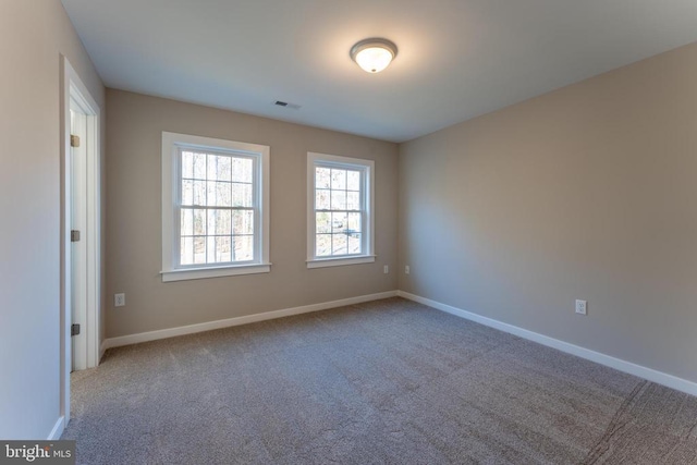 carpeted spare room with visible vents and baseboards