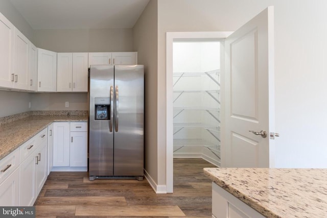 kitchen with stainless steel fridge with ice dispenser, light stone countertops, white cabinetry, and dark wood-type flooring