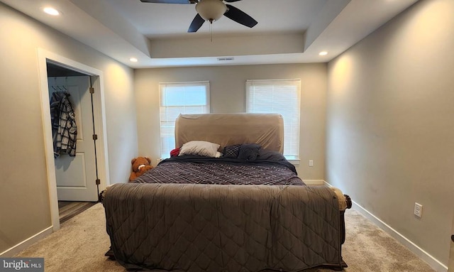 bedroom with light colored carpet, a raised ceiling, recessed lighting, baseboards, and visible vents