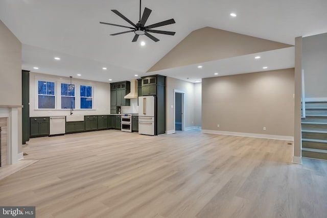 unfurnished living room featuring sink, a premium fireplace, ceiling fan, high vaulted ceiling, and light hardwood / wood-style floors