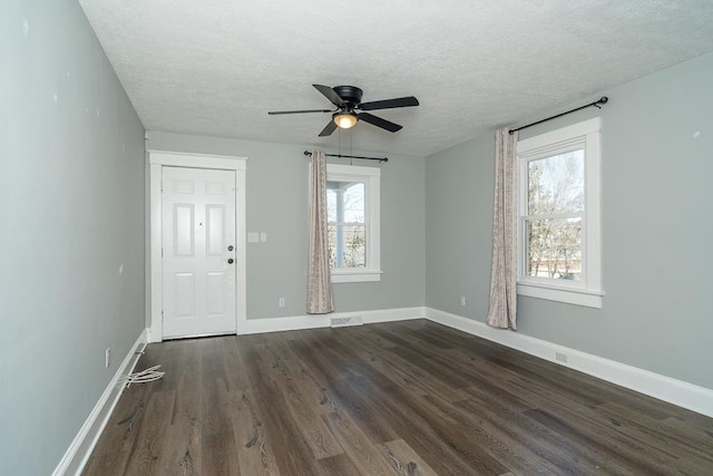 unfurnished room featuring baseboards, visible vents, a textured ceiling, dark wood-style flooring, and ceiling fan