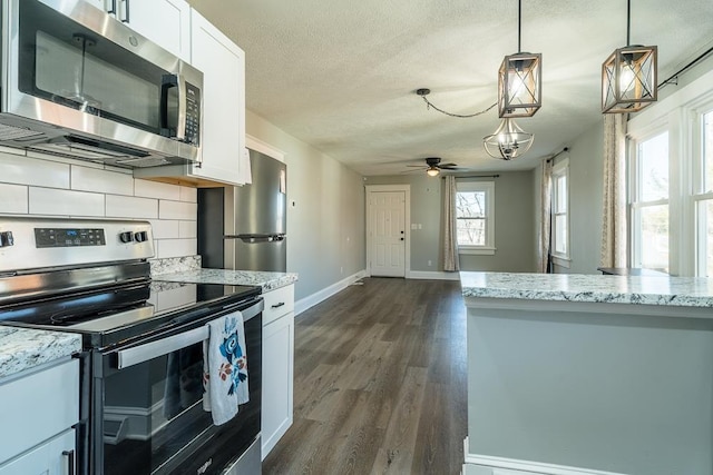 kitchen featuring hanging light fixtures, appliances with stainless steel finishes, dark wood finished floors, white cabinetry, and decorative backsplash