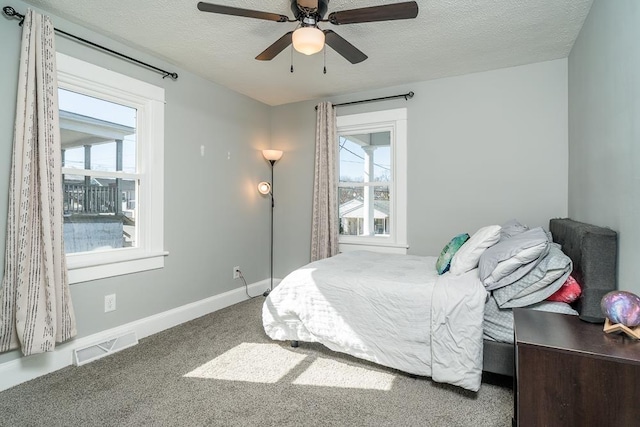 bedroom featuring visible vents, a ceiling fan, carpet, baseboards, and a textured ceiling