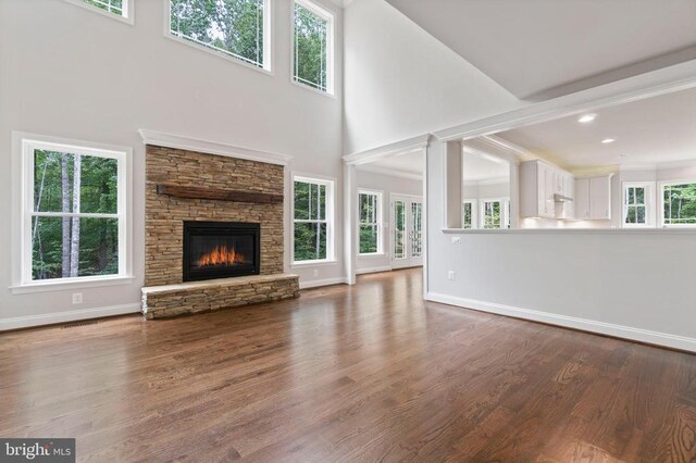 unfurnished living room with hardwood / wood-style floors, a fireplace, and a high ceiling