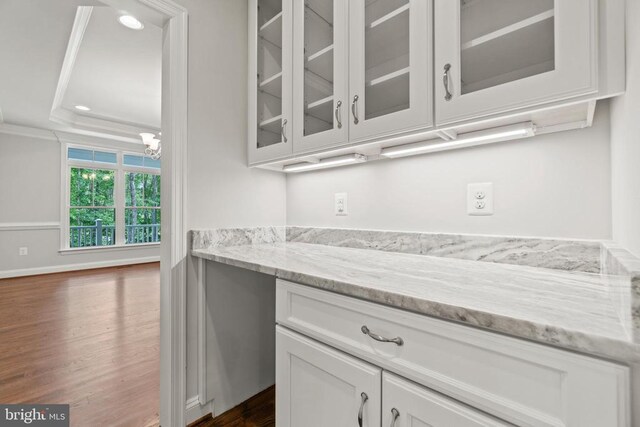 bar featuring crown molding, dark hardwood / wood-style floors, light stone counters, a tray ceiling, and white cabinets