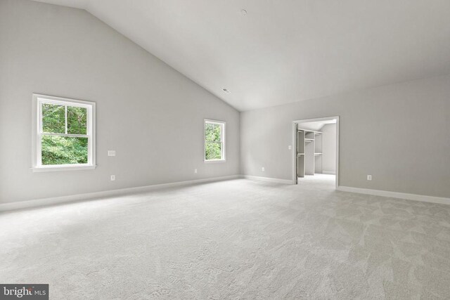 carpeted spare room with high vaulted ceiling