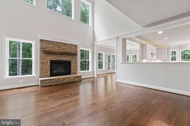 unfurnished living room with a towering ceiling, wood-type flooring, and a fireplace