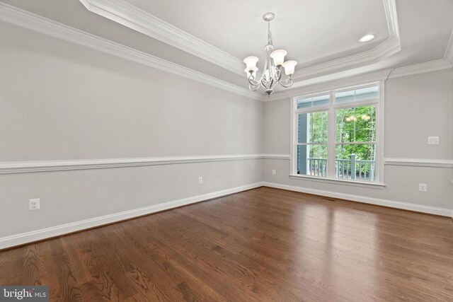 unfurnished room with ornamental molding, a raised ceiling, hardwood / wood-style floors, and a notable chandelier