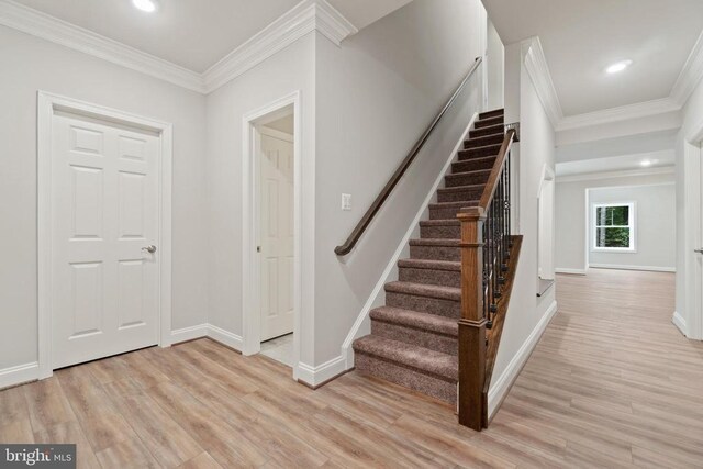 stairway with hardwood / wood-style flooring and crown molding