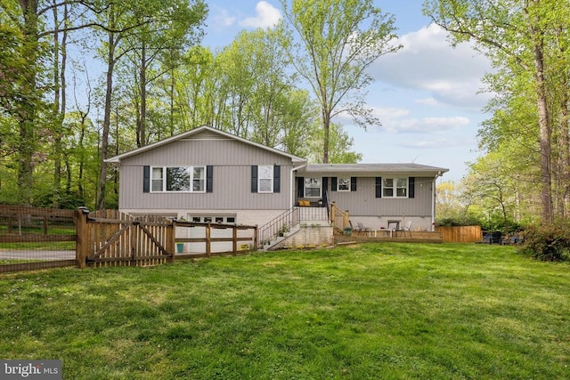 rear view of property with fence, a gate, and a lawn