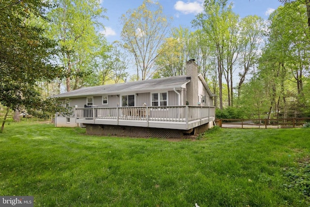 back of house featuring a lawn, a chimney, a deck, and fence